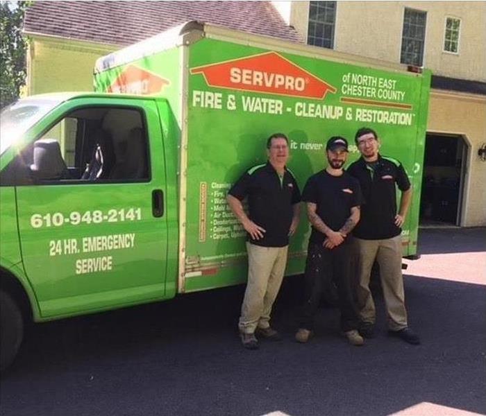 Three people in front of a green truck